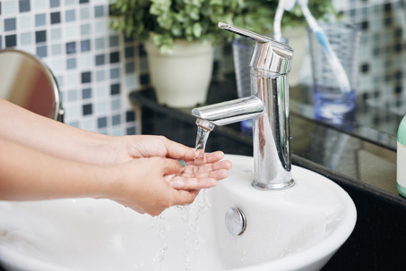 person washing hands with soft water from sink